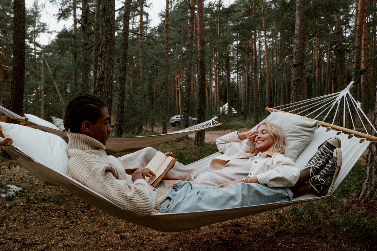 a couple reading in a hammock in a densely forested area 