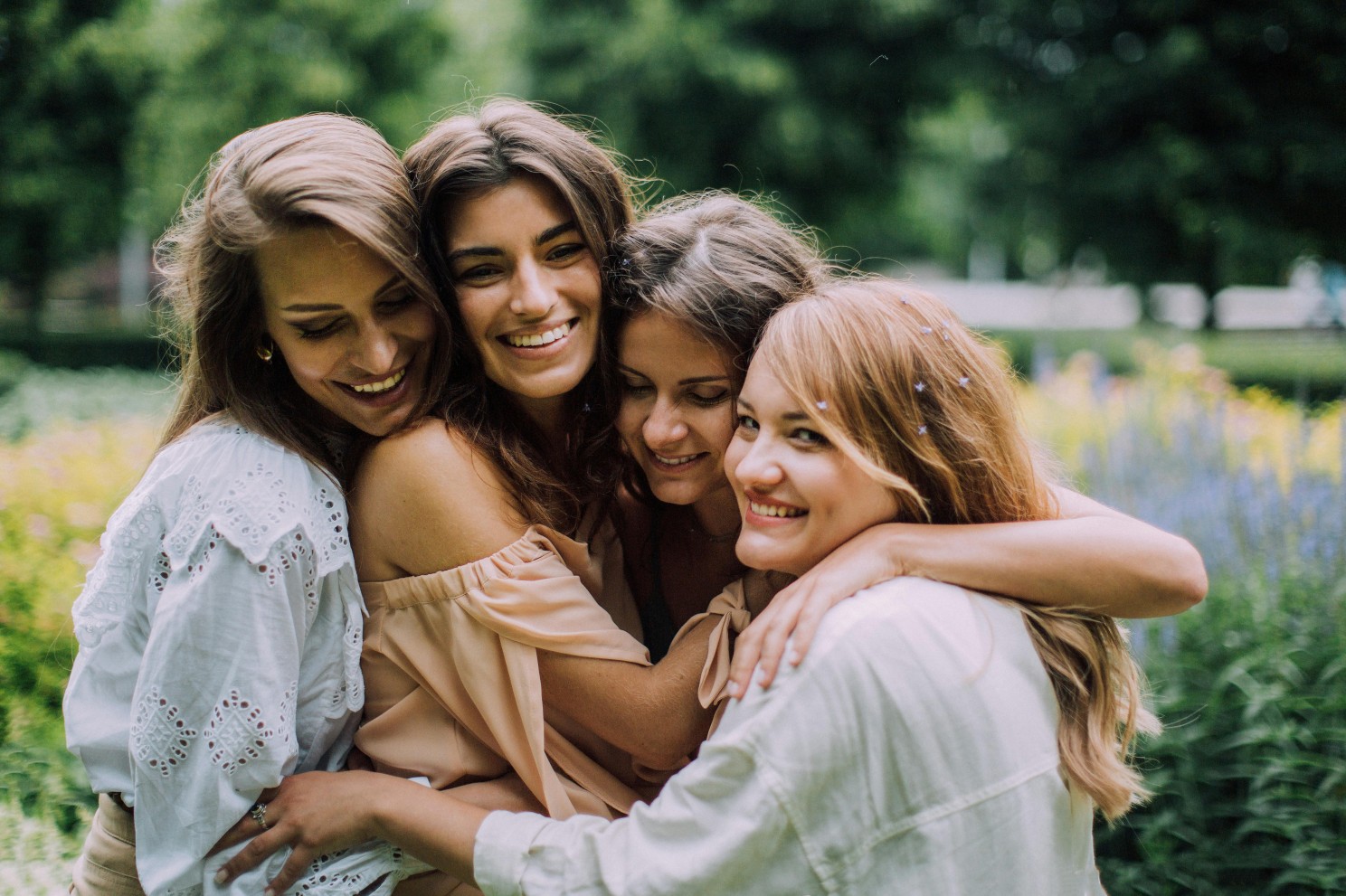 A group of 4 women hugging in a garden