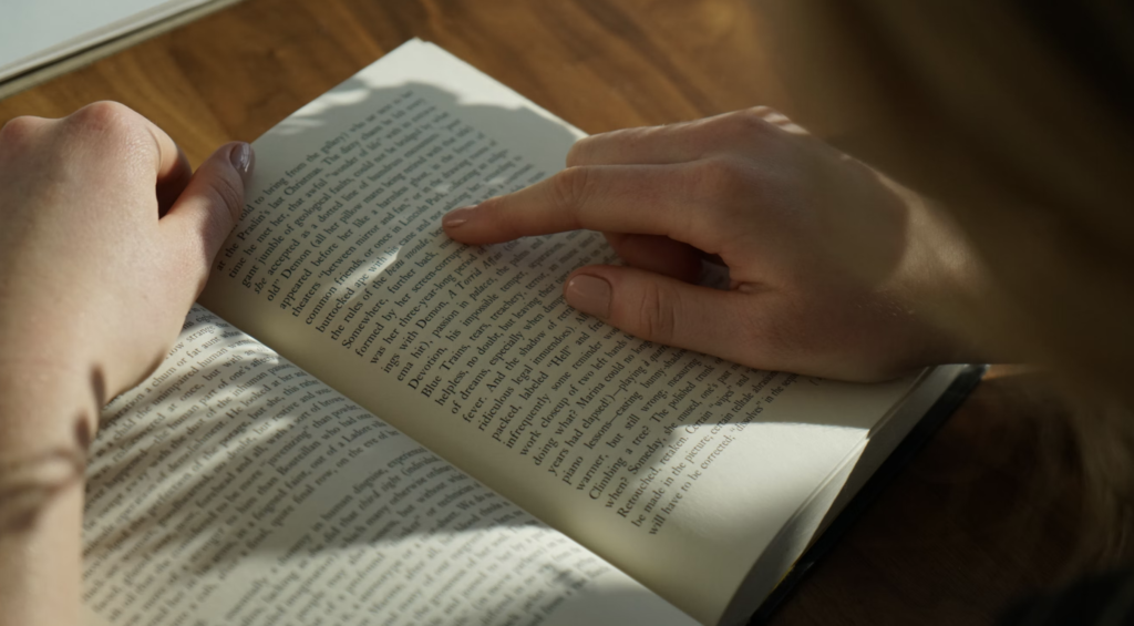 pair of hands finger-reading a book in a lap