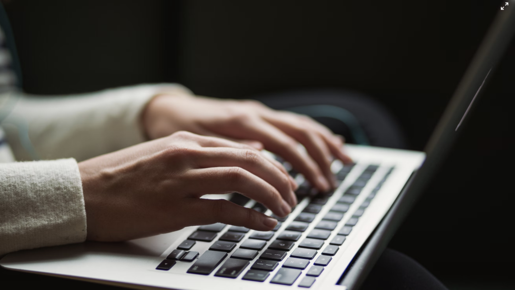 a pair of hands typing on a macbook keyboard 