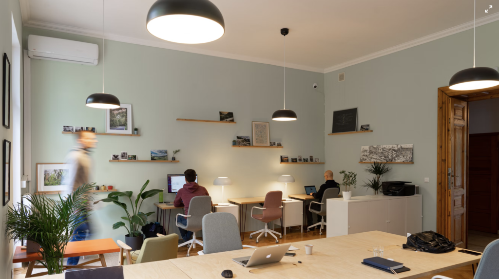 an office with an array of macbooks on tables, and working people in the background 