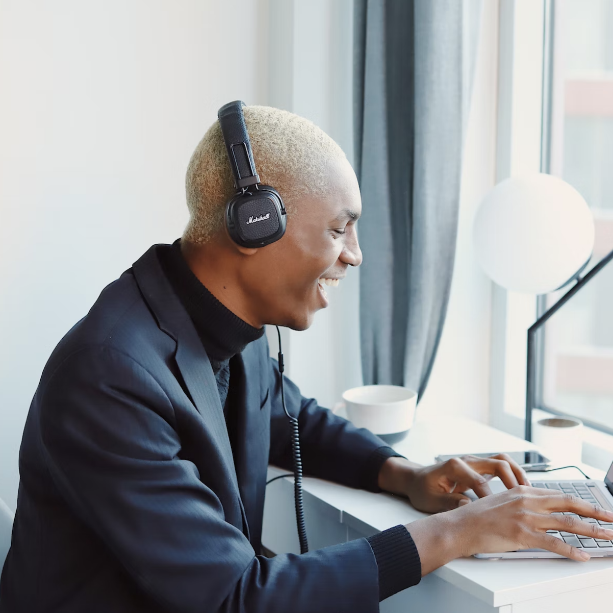 a man in headphones looking overjoyed whilst using a laptop computer