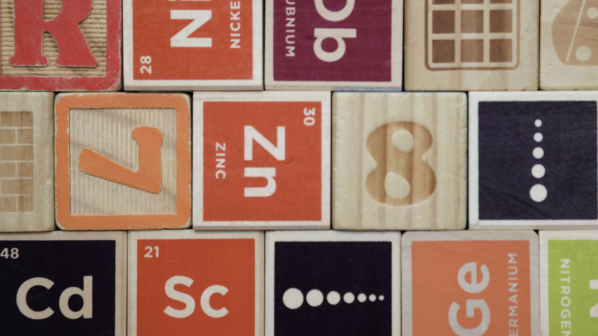 a series of wooden blocks with numbers and chemical elements on, in red and lime green 