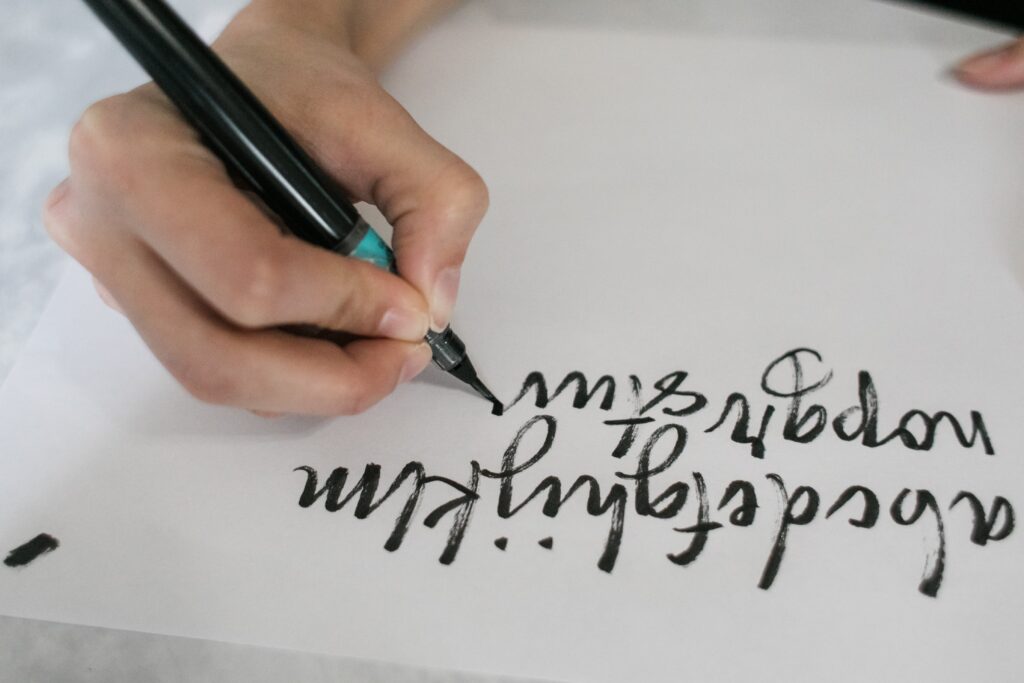A hand transcribing the alphabet using a brush pen