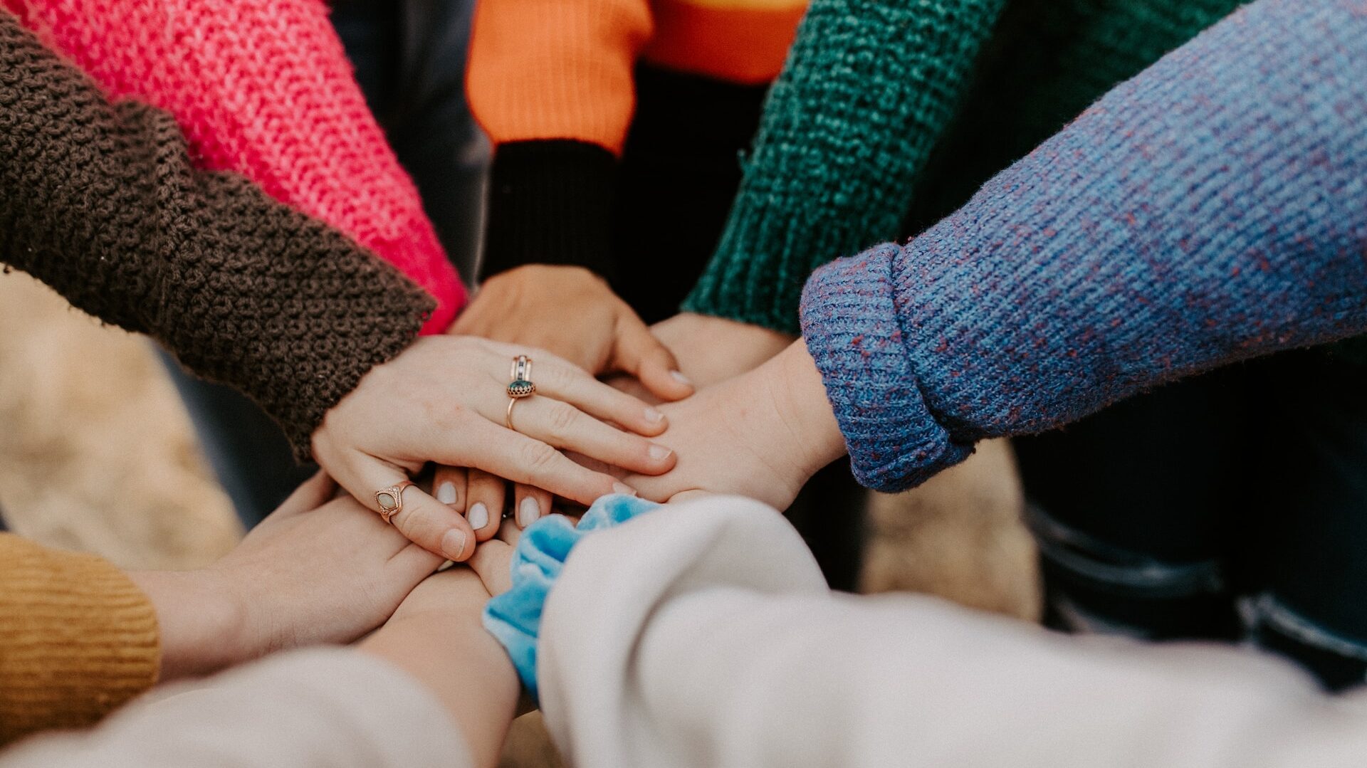 a circle of hands in different coloured sweaters 