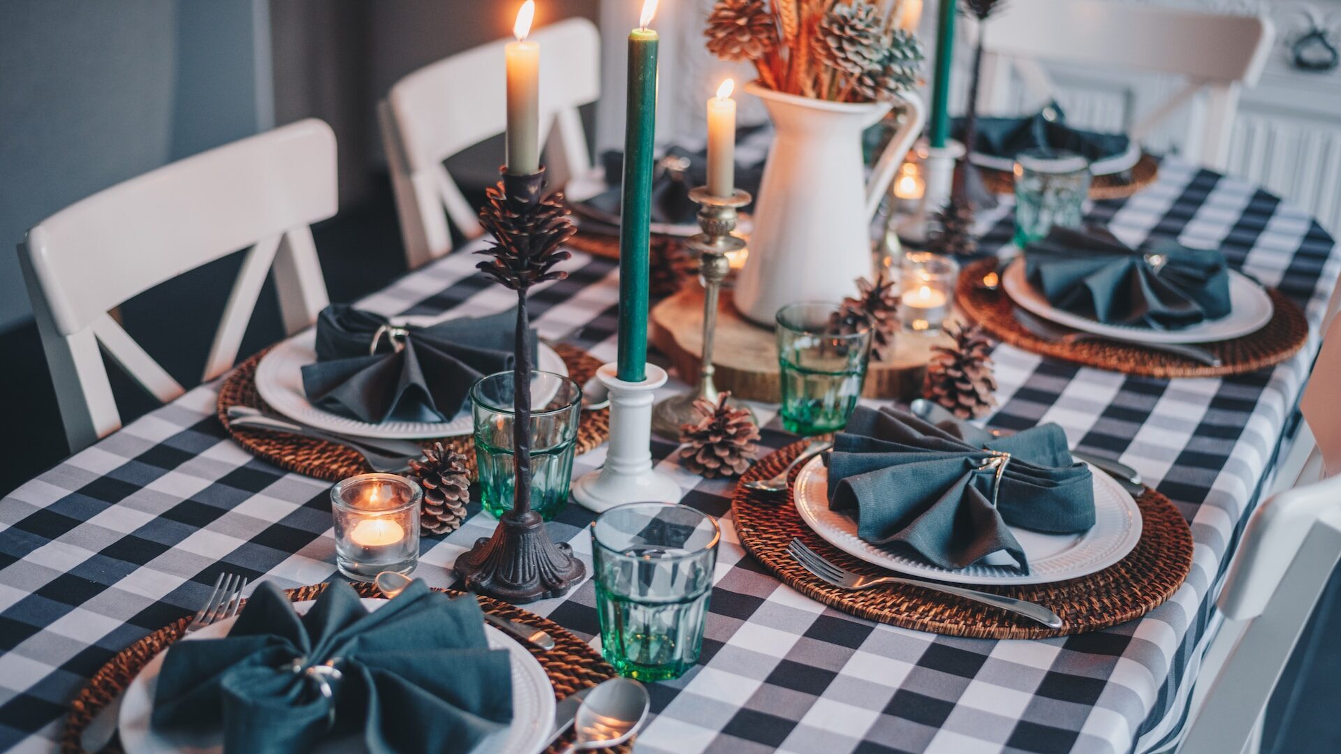 a table laid in shades of green, with festive decorations, candles and pine cones. 