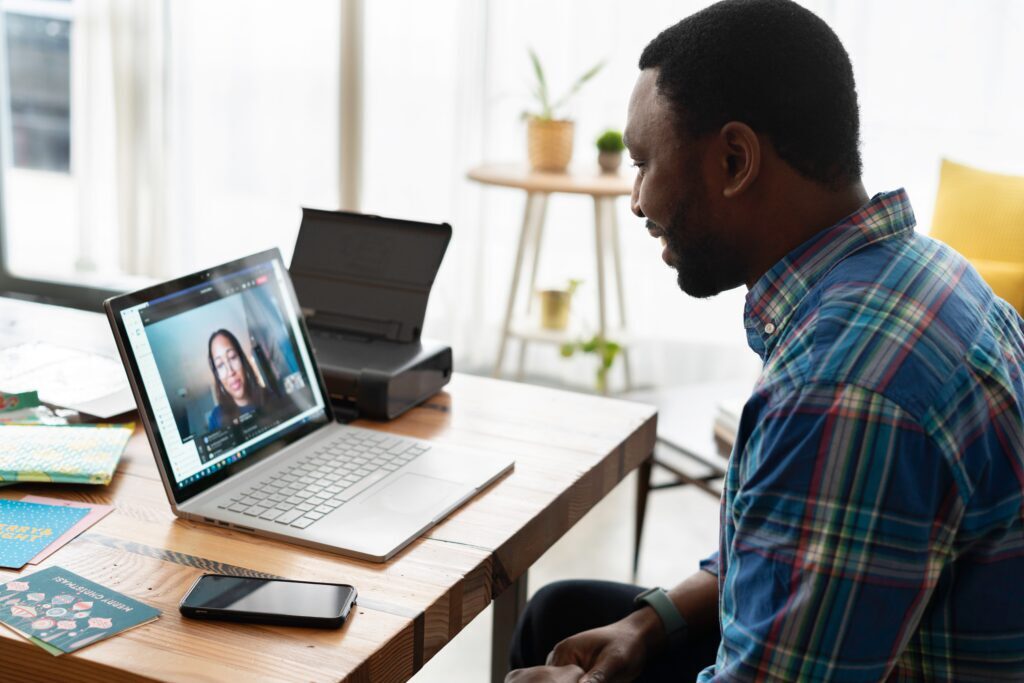 man in check shirt having a conversation with a woman via a laptop