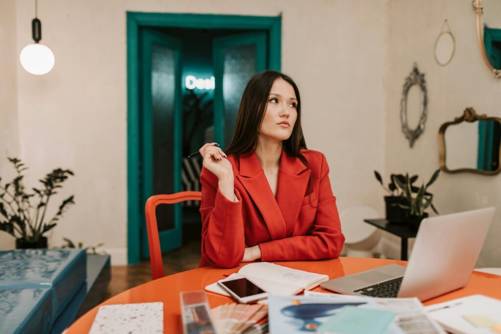 Woman in a smart red business suit sitting at a laptop in a home office 