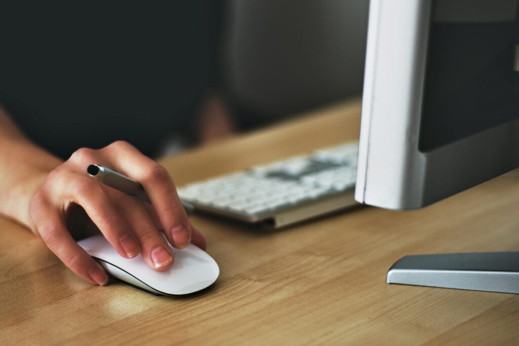 Hand on an Apple mouse on a desk