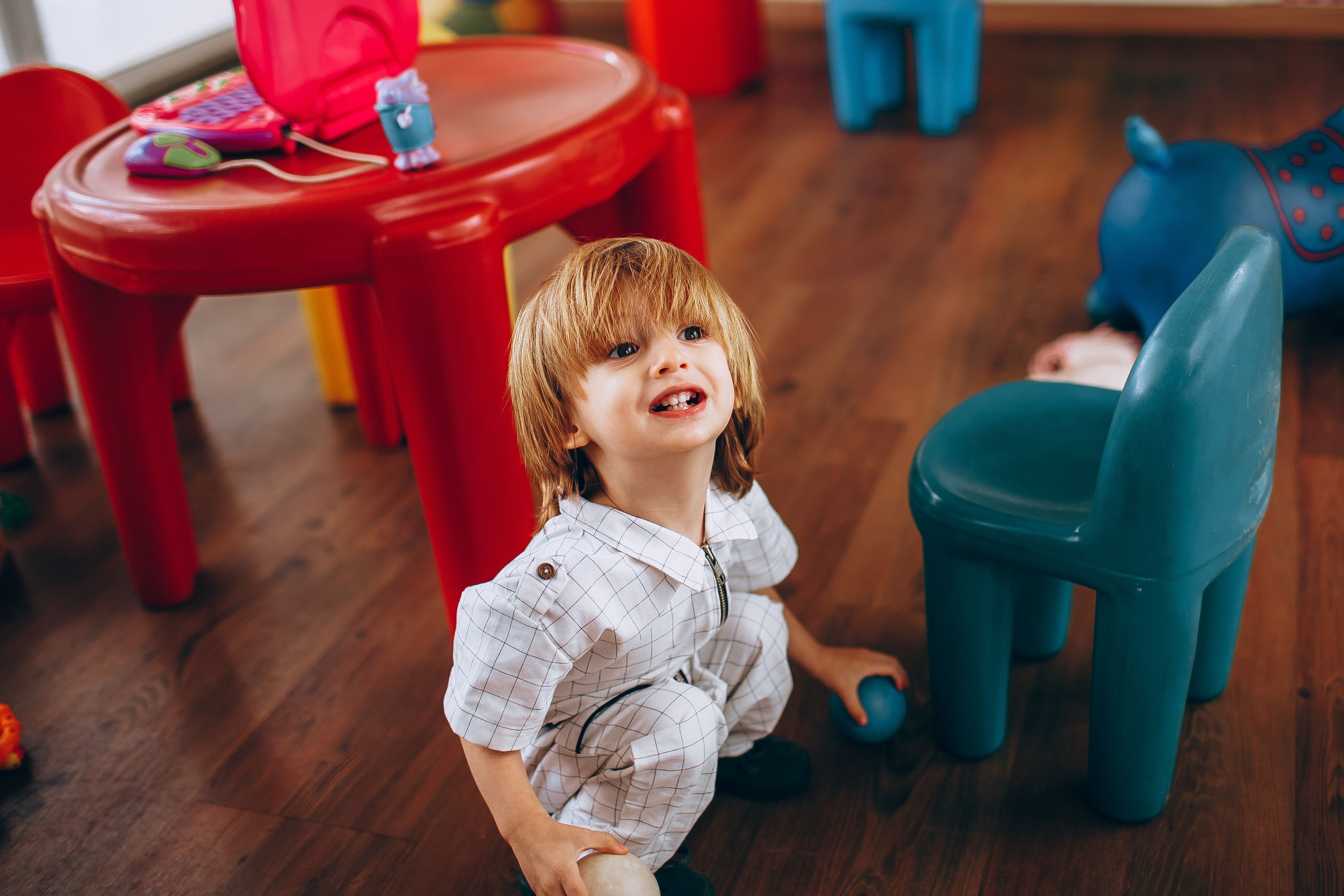 little boy on the floor smiling playing with a small ball