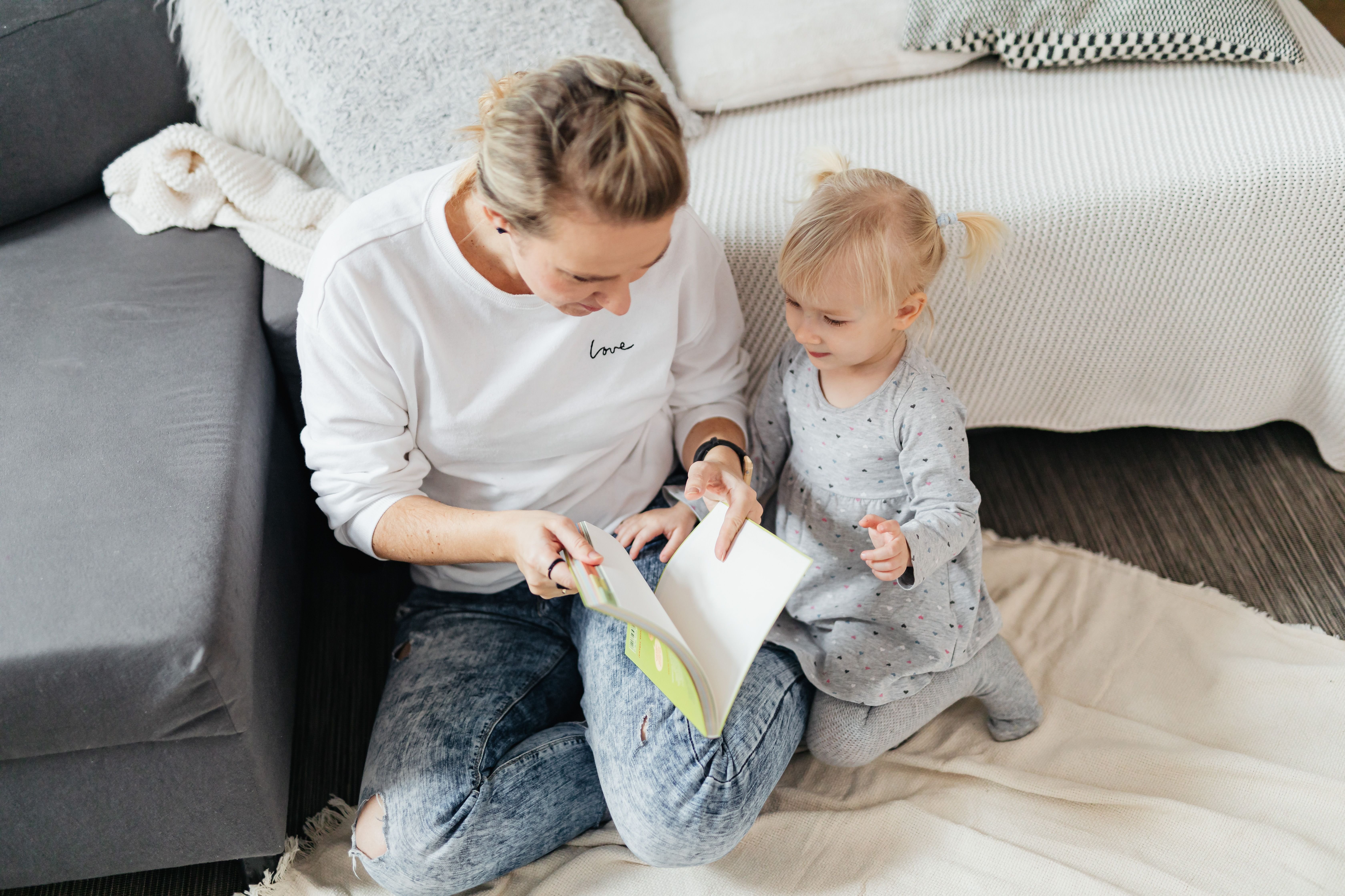 woman reading a book to a little girl