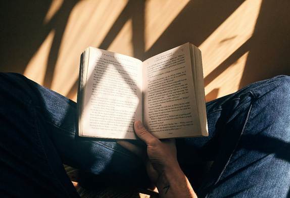 Person sitting crossed leg reading a book
