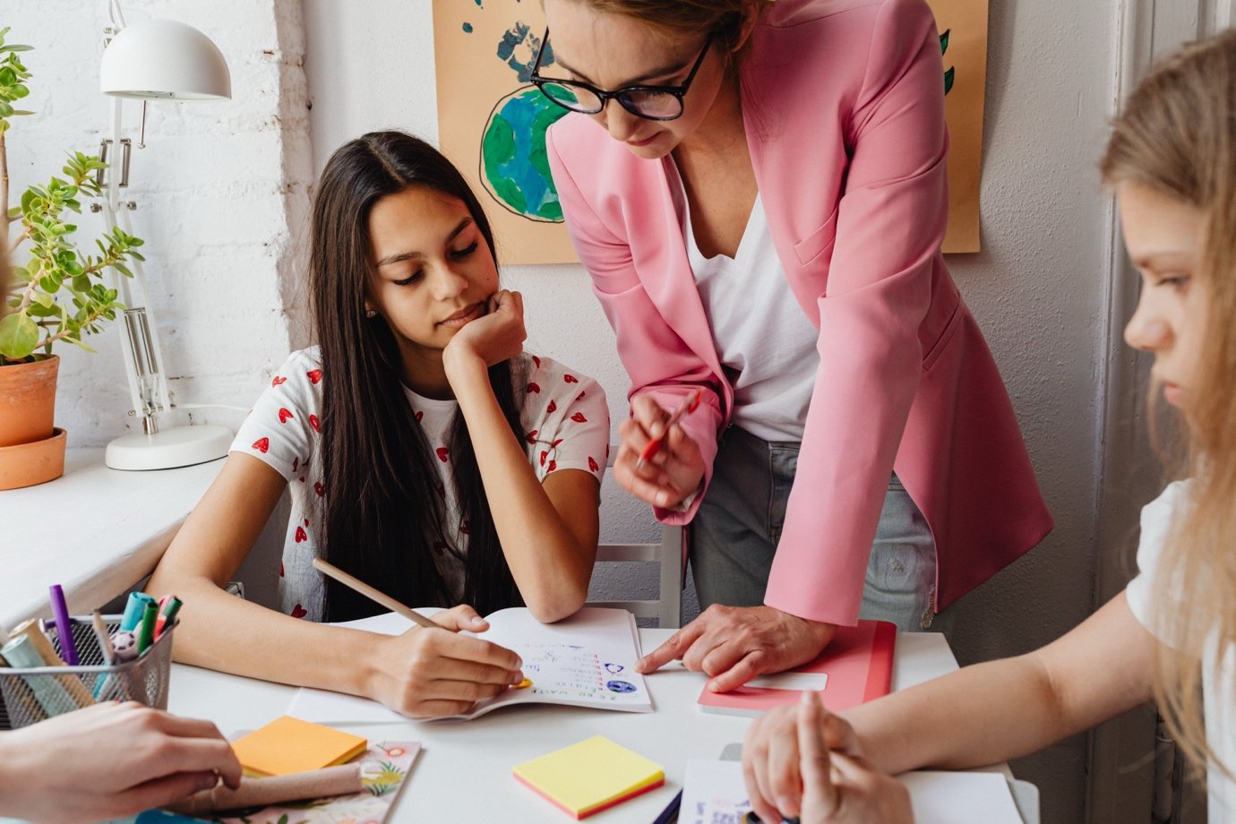 a woman helping two children with their work at a desk